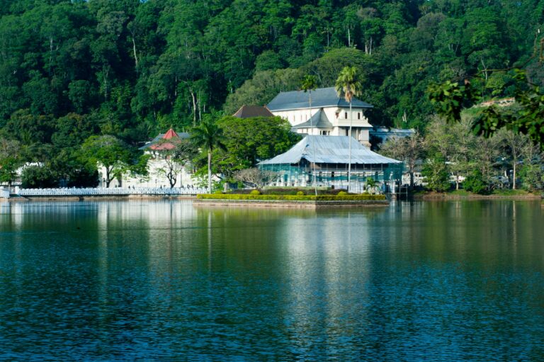 Serene view of Kandy Lake and Temple of the Tooth surrounded by lush greenery in Kandy, Sri Lanka.
