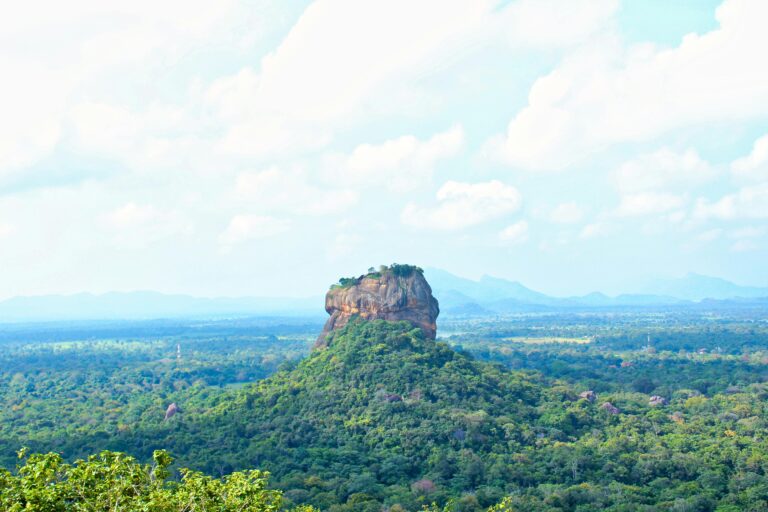 A breathtaking view of Sigiriya Rock surrounded by lush greenery under a blue sky in Sri Lanka.