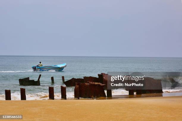 Tamil man drives a boat past the rusted metal remains of the Farah 3 ship by the ocean along the beach in Mullaitivu, Sri Lanka. This is one of the many scars from the 26-year long civil war between the Sri Lankan Army and the LTTE (Liberation Tigers of Tamil Eelam). The Farah 3 ship was a Jordanian owned merchant ship. While it was on its way from the coast of Andhra Pradesh in India to South Africa, it developed engine trouble, and had to anchor off the coast of Mullaitivu. The LTTE Sea Tigers hijacked the ship and took its crew prisoner in December 2006 and dragged the ship closer to the coast where it ran aground at the present location. The ship was used by the LTTE Sea Tigers for training purposes and some of the ships metal from the hull was removed and used to make naval boats and submarines. (Photo by Creative Touch Imaging Ltd./NurPhoto via Getty Images)